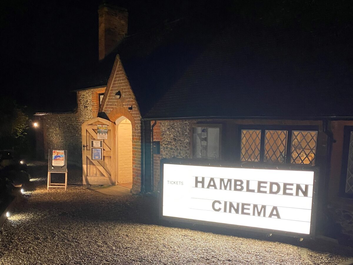 Hambleden Village Hall on a screening night, with the lit Hambleden Cinema sign outside